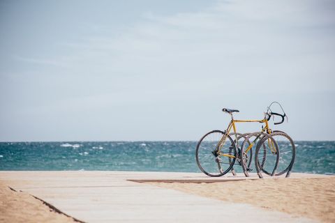 Yellow road bicycle resting on wooden boardwalk overlooking turquoise ocean and sandy beach