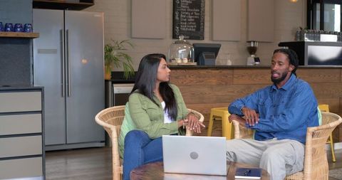 Diverse coworkers discussing project in cozy coffeehouse lounge with laptop