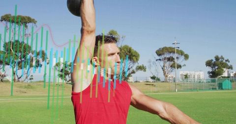 Male athlete lifting kettlebell overhead on outdoor field with fitness data analytics