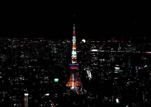 Tokyo Tower is brightly lit against the dark night sky, surrounded by the sprawling city lights of Tokyo. Ideal for use in travel brochures, blogs about Tokyo's landmarks, urban photography collections, articles about iconic structures, and imagery showcasing Japan's nightlife.