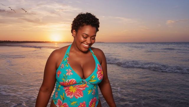 Smiling woman wearing turquoise floral swimsuit walking in surf at golden hour