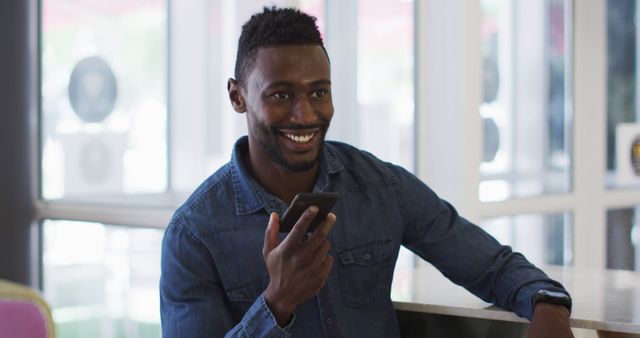 Cheerful Man in Denim Shirt Speaking on Smartphone Indoors - Download Free Stock Images Pikwizard.com