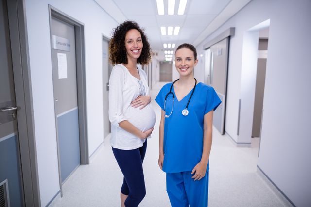 Portrait of doctor and pregnant womans standing in corridor of hospital