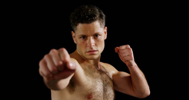 Portrait of man boxing on black background