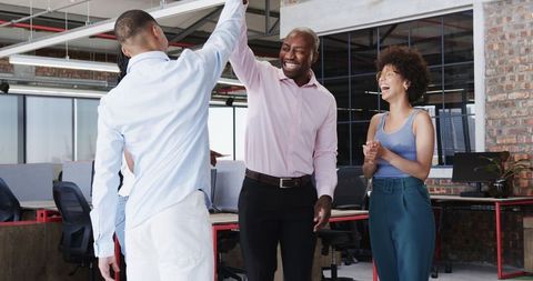 Colleagues High-Fiving in Modern Collaborative Office Space