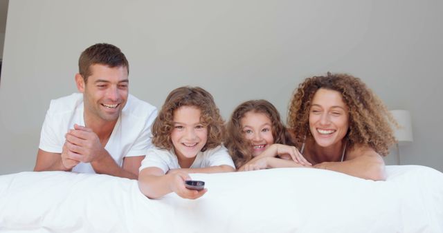 Happy family enjoying movie night on bed - Download Free Stock Images Pikwizard.com