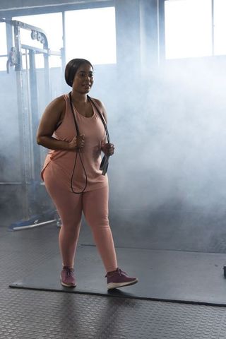 Plus-size african-american woman exercising with jump rope in urban gym