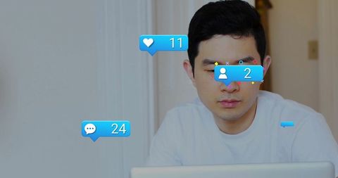 Asian man working from home at laptop with social media notifications, remote work focus