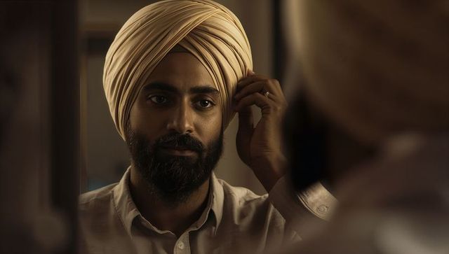 Man adjusting cream turban at mirror warm portrait grooming ritual intimate lighting