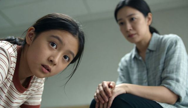 Young girl leaning forward while mother watching and comforting in pediatric clinic