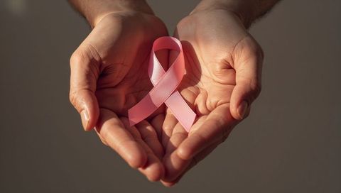 Hands Gently Holding Pink Ribbon for Breast Cancer Awareness