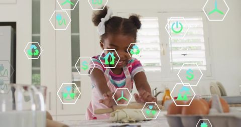 Young girl kneading dough on kitchen counter with augmented reality sustainability icons