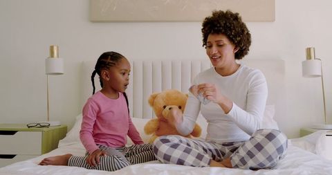 Mother and Daughter Bonding Over Bedtime Fun with Teddy Bear
