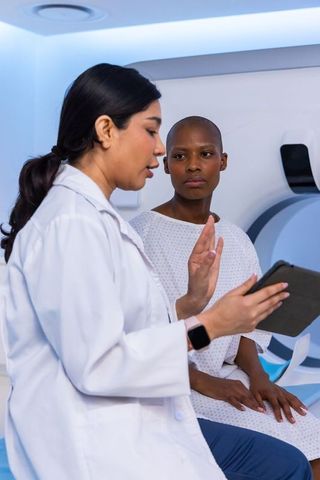 Doctor discussing mri scan with patient inside radiology suite using tablet