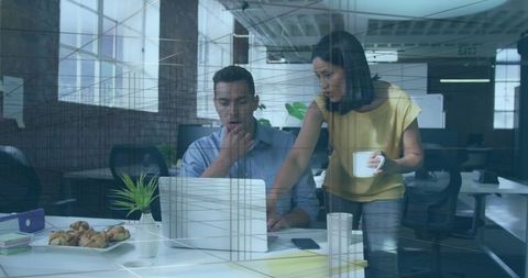 Colleagues collaborating on laptop in modern open-plan office