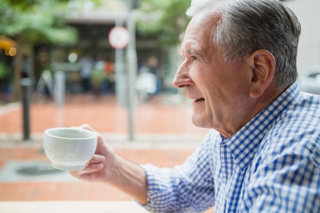Senior man holding a coffee cup in outdoor cafe