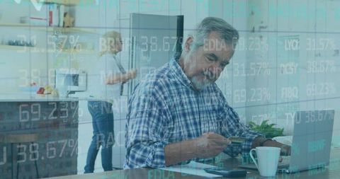 Senior man paying online amidst financial data graphics