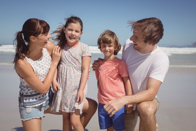 Happy siblings with parents at beach during sunny day