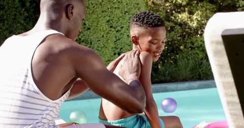 Father Applying Sunscreen to Son by Poolside for Summer Fun