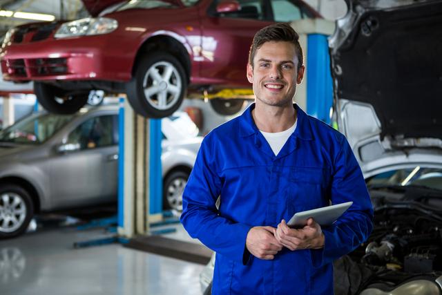 Portrait of mechanic holding digital tablet at repair garage