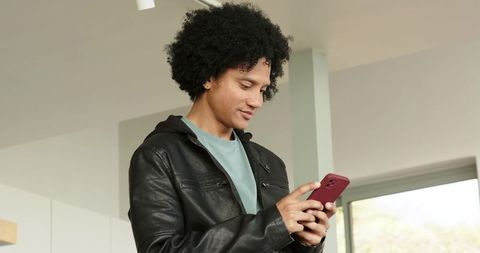 African american man tapping smartphone in modern minimalist home interior