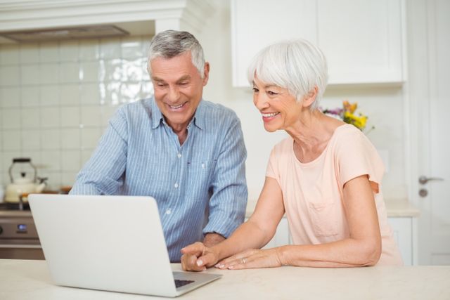 Senior couple using laptop in kitchen at home
