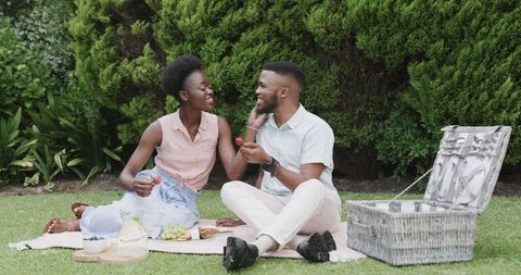 Young Couple Sharing a Picnic in Lush Green Park