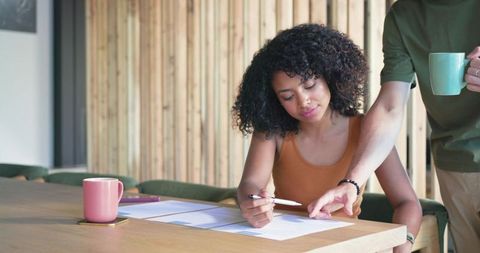 Woman reviewing documents with coworker pointing, casual workspace collaboration and planning