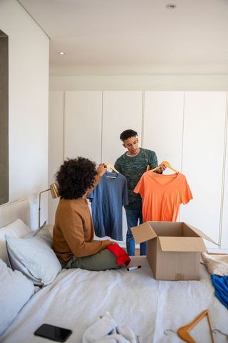 Diverse friends unpack new clothing choices at home