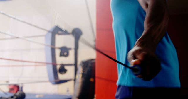 Athlete focusing on fitness training and cardio exercise by jumping rope in the boxing gym. Ideal for fitness blogs, gym promotions, sports training programs, and articles related to health and physical fitness.