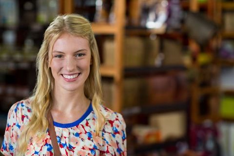 Smiling woman shopping in rustic boutique store with floral blouse