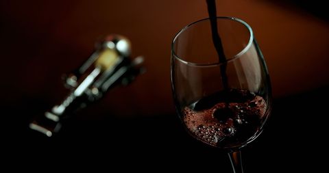 Red Wine Pouring into Glass with Corkscrew in Elegant Setting