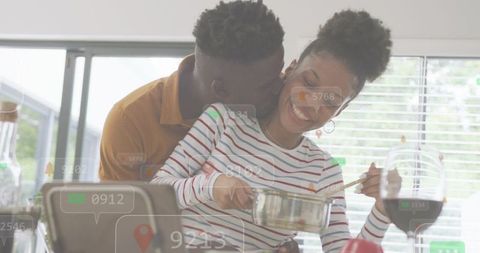 Romantic couple cooking in sunlit kitchen sharing playful kiss while stirring saucepan