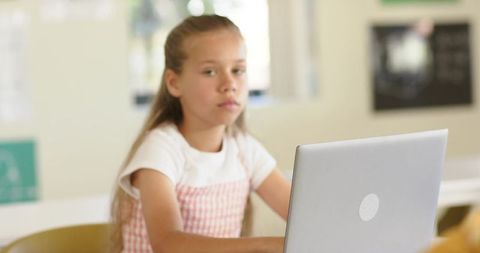 Teenage girl working on laptop in classroom focusing on remote study and digital learning