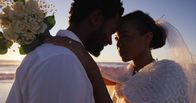 African american couple in love getting married, looking at other on the beach at sunset. marriage, love and romance, holiday by the sea.