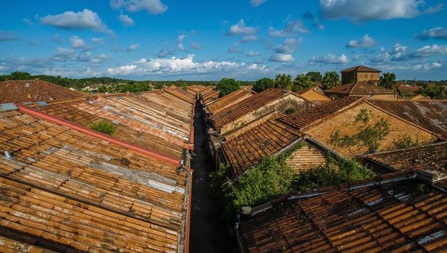 Sunlit Terracotta Rooftop Rows with Narrow Alleyway, Weathered Tiles and Tower from Aerial View