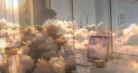 Businessman Working with Laptop Overlaid by Dreamy Clouds