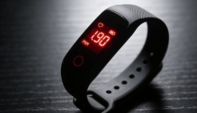 Black fitness tracker displaying 190 bpm heart rate on red led screen with silicone strap