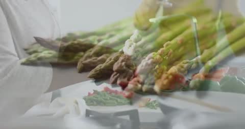 Son turning faucet and rinsing asparagus while handing spears to mother slicing red pepper