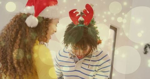 Couple sharing cozy christmas moment at home wearing santa hat and reindeer antlers