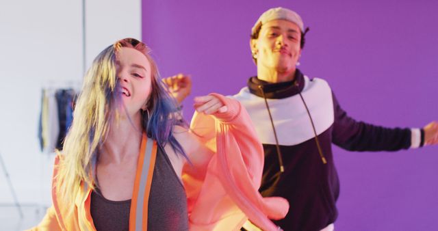 Two young friends are joyfully dancing in a colorful studio. The scene is vibrant and energetic, with a focus on fun and happiness. This visual is perfect for promoting dance classes, lifestyle products, youth engagement activities, or any media related to music and youth culture.