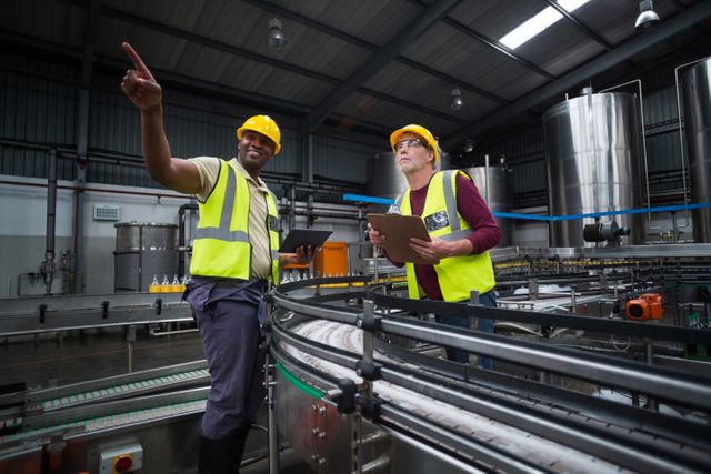 Two factory workers looking up in drinks production plant