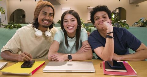 Young diverse friends collaborating around laptop at cozy coworking lounge
