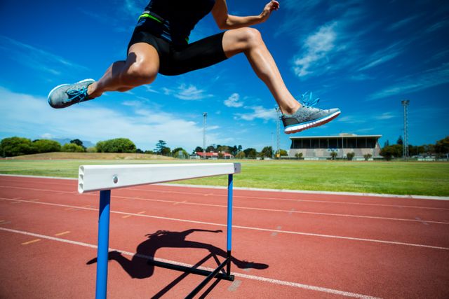 Female Athlete Hurdling on Track with Blue Sky - Download Free Stock Photos Pikwizard.com