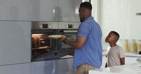 Father and Son Baking Pizza Together in Modern Kitchen