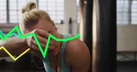 Female athlete pausing and resting after intense boxing training with neon ecg line overlay