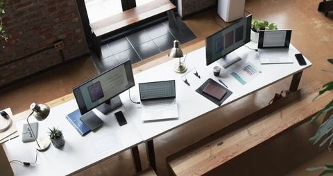 Creative workstations in modern office with blank screens and notebooks