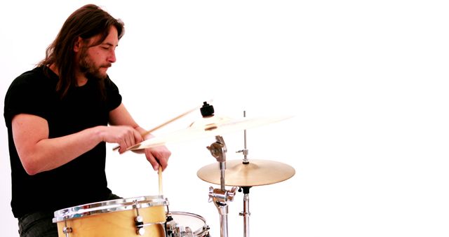 Musician energetically playing drum set, ideal for music events, band promotions, or musical instrument advertisements. Great visual for music-related websites, concert posters, or articles on drumming techniques.