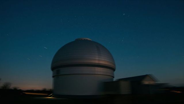 Towering observatory dome glowing beneath sweeping star trails at twilight for astronomy visuals