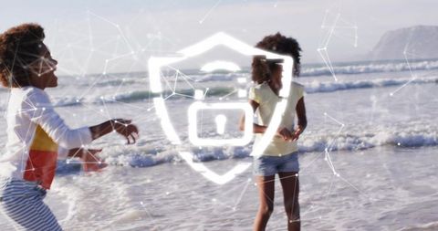 Children playing on beach splashing surf with digital security shield overlay concept